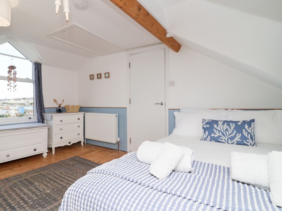 A bedroom with a bed, dresser, and window at Still Waters in Brixham
