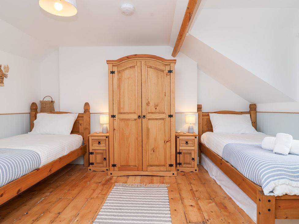 A bedroom with two beds and a wardrobe at Still Waters in Brixham