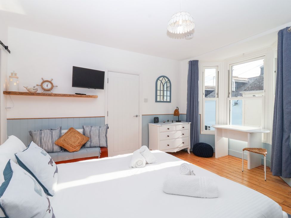 A bedroom with a bed, sofa, television, and desk at Still Waters in Brixham