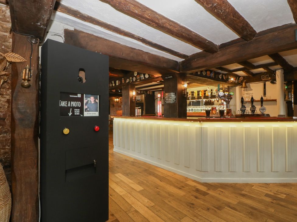 A bar with a photo booth and wooden beams at Penny Farthing Inn Aston Crews near Ross-On-Wye