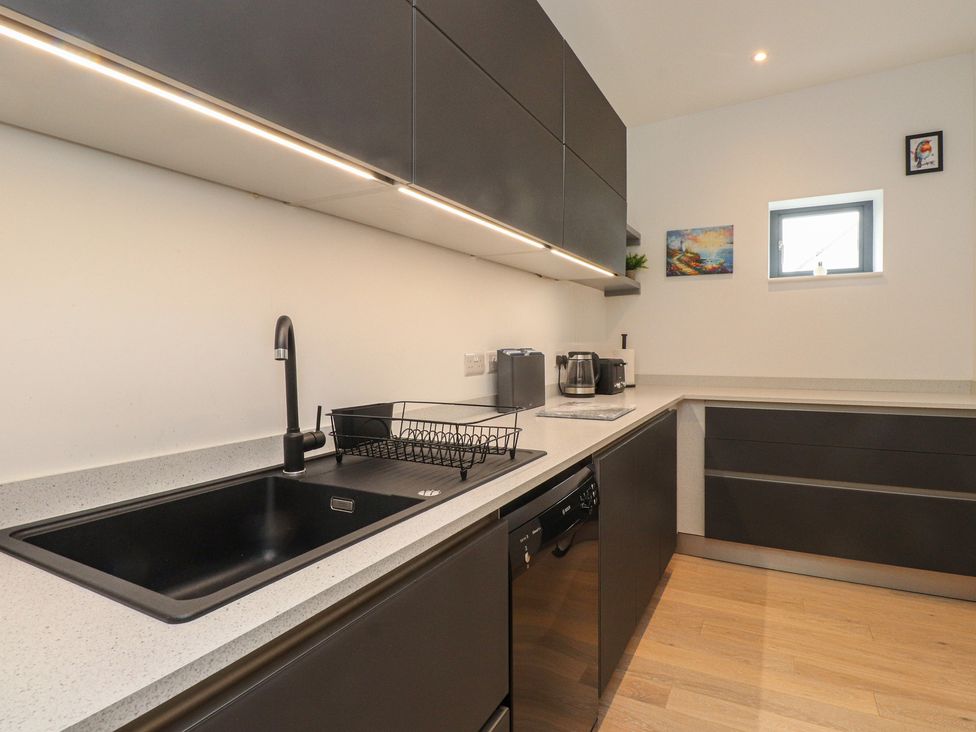 A kitchen with a sink, counter, and appliances at 70 Deganwy Road in Deganwy