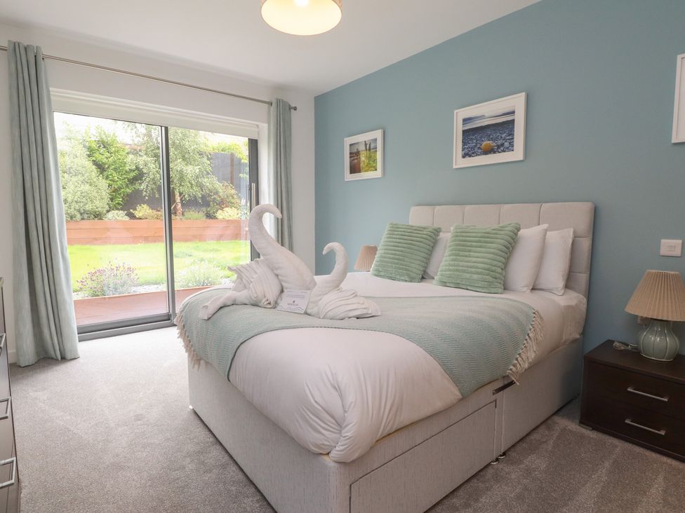 A bedroom with a bed and sliding doors to the garden at 70 Deganwy Road in Deganwy