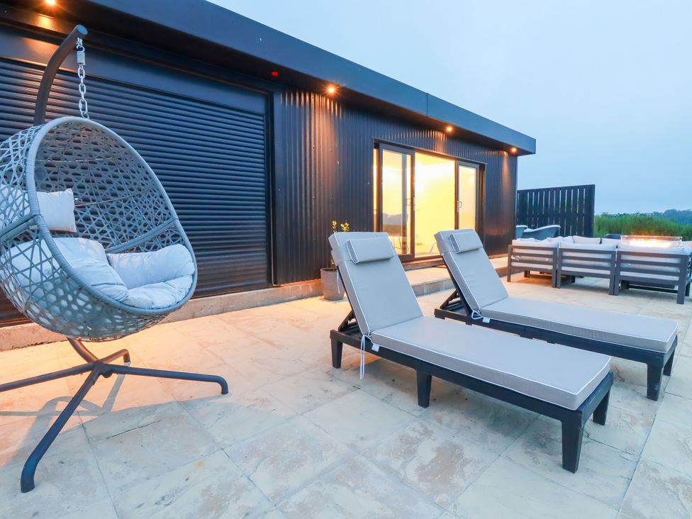 An outdoor area with sun loungers and a hanging chair at The Lake Boat exclusive retreat Black Cross near St Columb Major