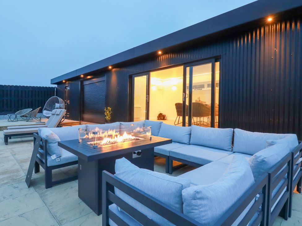 An outdoor patio with a fire pit and seating area at The Lake Boat exclusive retreat Black Cross near St Columb Major