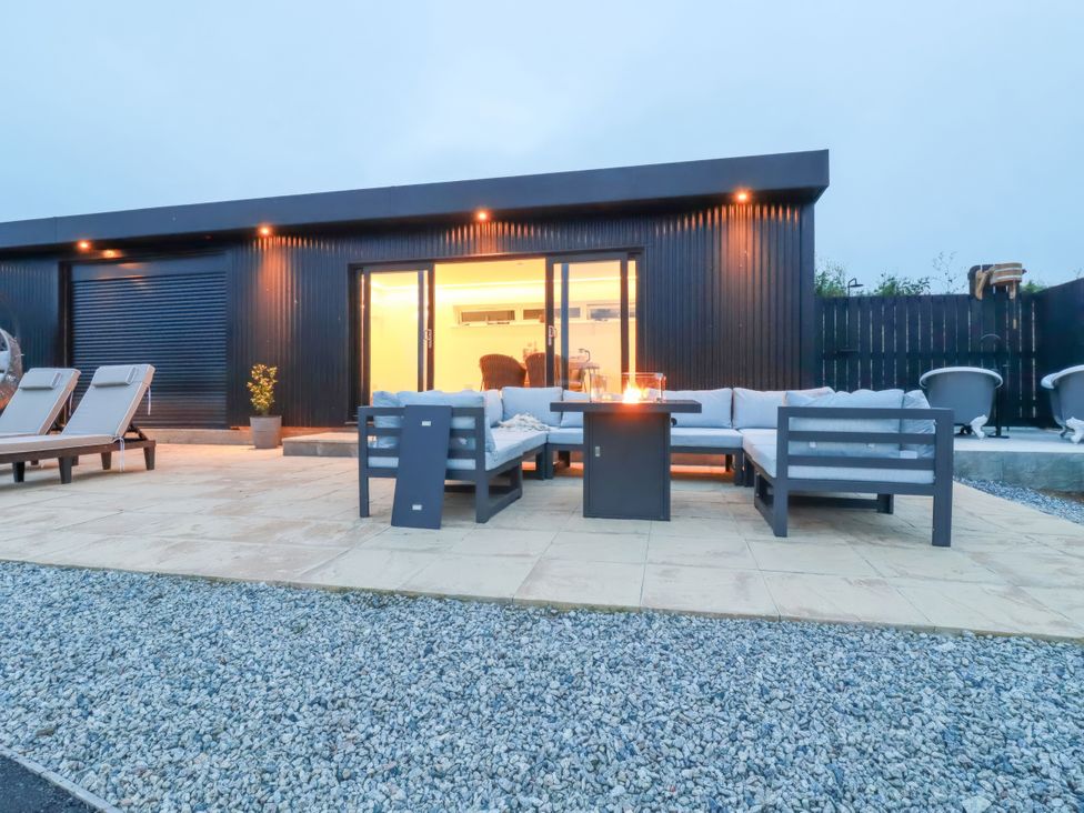 An outdoor patio with seating and a fire pit at The Lake Boat exclusive retreat Black Cross near St Columb Major