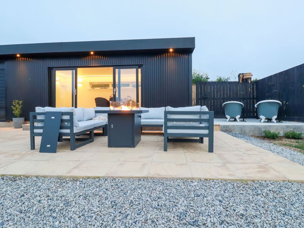 An outdoor patio with a fireplace and seating at The Lake Boat exclusive retreat Black Cross near St Columb Major