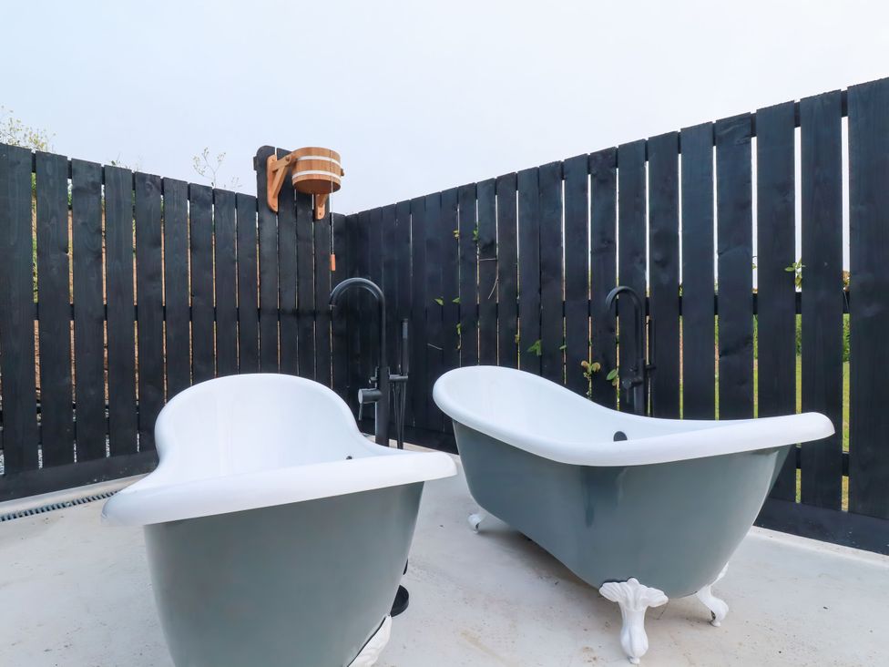 Two bathtubs and an outdoor shower at The Lake Boat exclusive retreat Black Cross near St Columb Major