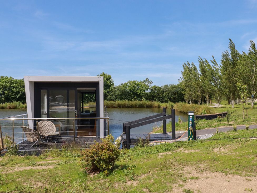 A floating house by water with a deck and charging station at The Lake Boat exclusive retreat Black Cross near St Columb Major