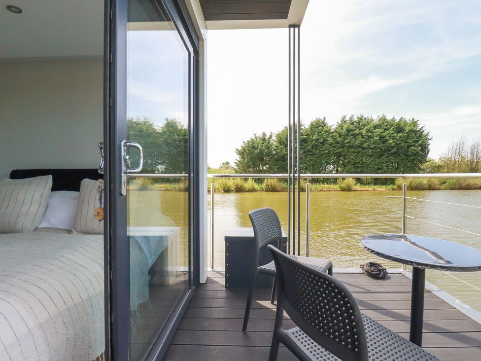 An outdoor area with table and chairs overlooking the river at The Lake Boat exclusive retreat Black Cross near St Columb Major
