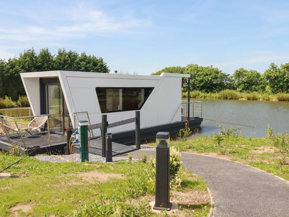 A houseboat on water with a pathway at The Lake Boat exclusive retreat Black Cross near St Columb Major