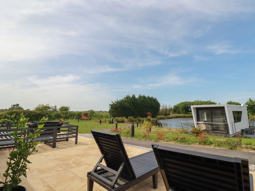 An outdoor area with deck chairs and a lake at The Lake Boat exclusive retreat Black Cross near St Columb Major
