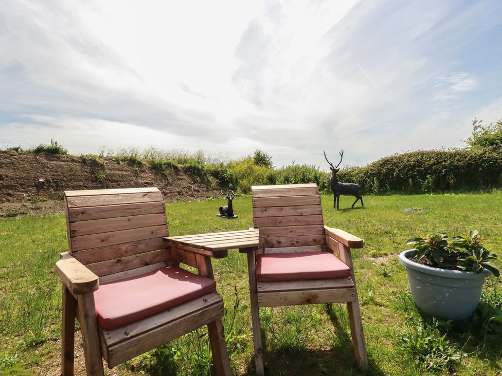 Two wooden chairs and a table in a garden at The Lake Boat exclusive retreat Black Cross near St Columb Major