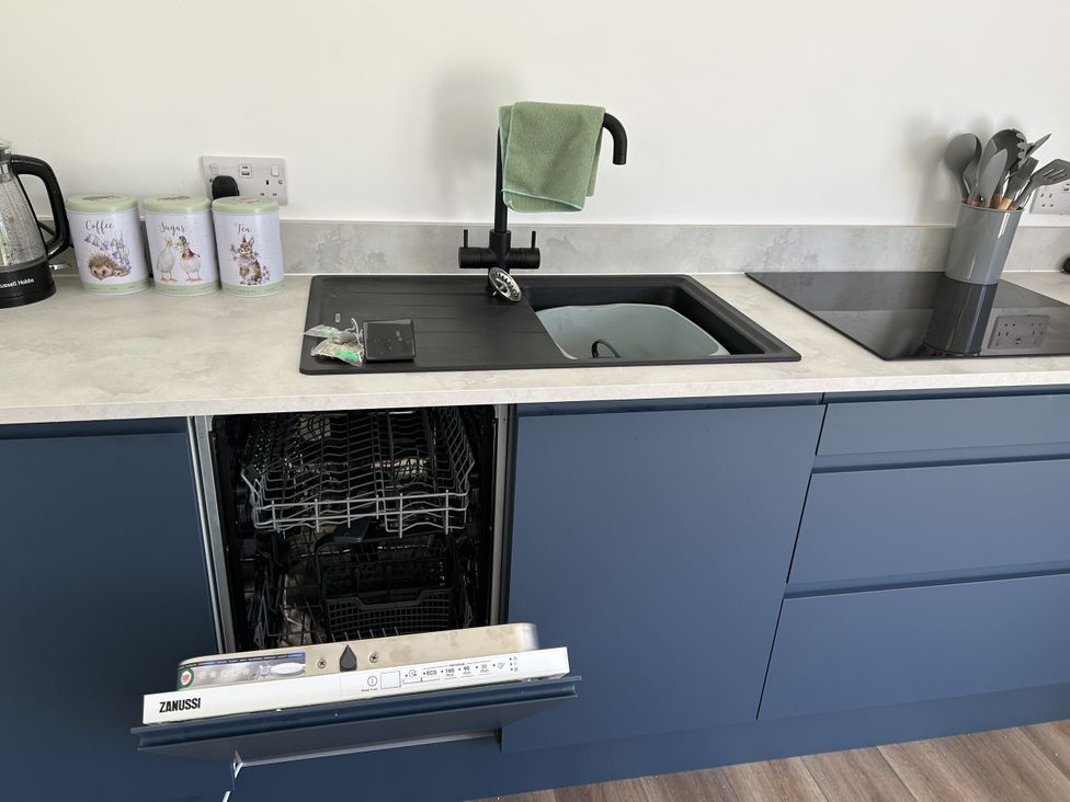 A kitchen with a sink, dishwasher, kettle, canisters, and utensils at The Lake Boat exclusive retreat near Black Cross St Columb Major