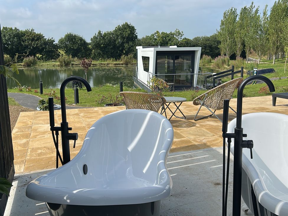 Two bathtubs overlooking a water body at The Lake Boat exclusive retreat Black Cross near St Columb Major