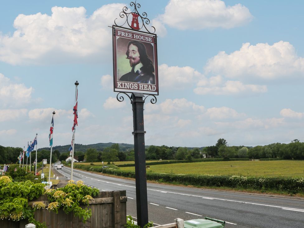 A roadside sign for Kings Head with flags and green fields at The Annex in 