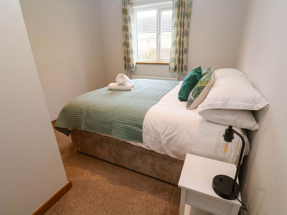 A bedroom with a bed and bedside table at Byron’s Retreat in Crantock