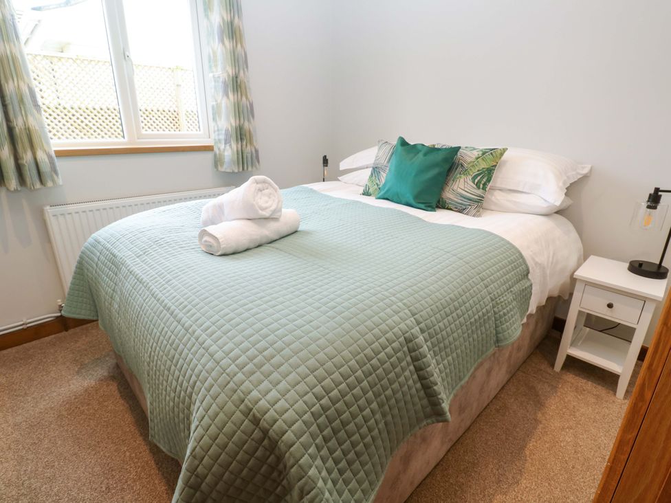 A bedroom with a bed and bedside table at Byron’s Retreat in Crantock