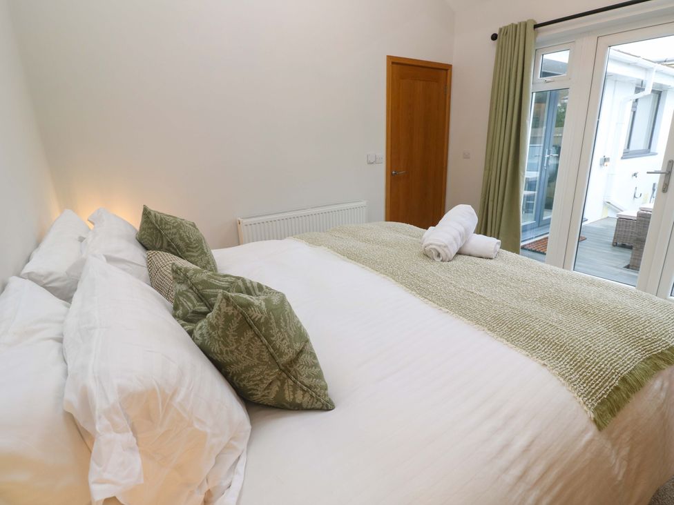 A bedroom with a bed and towels at Byron’s Retreat in Crantock