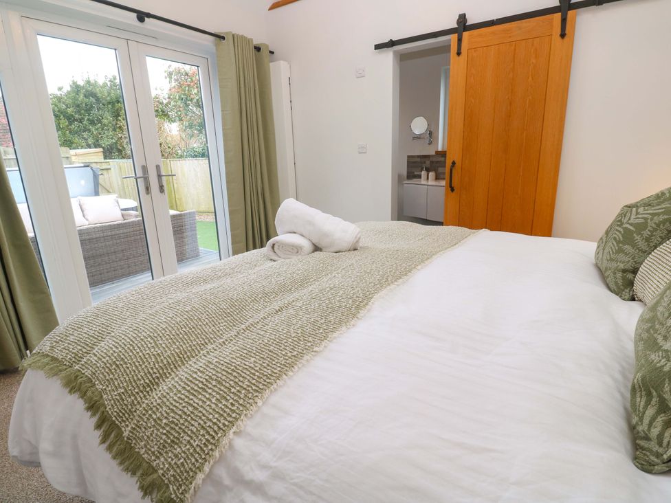 A bedroom with a bed and sliding doors to an outdoor area at Byron’s Retreat in Crantock