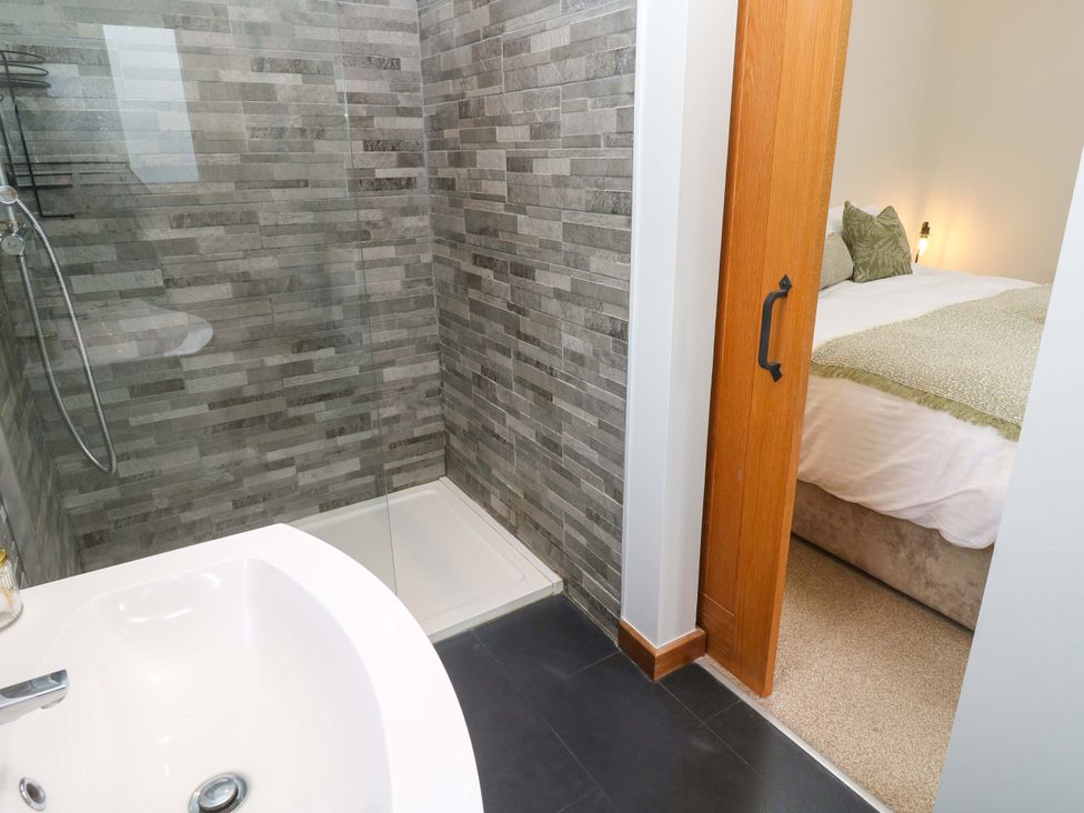 A bathroom with a shower and bathtub at Byron’s Retreat in Crantock