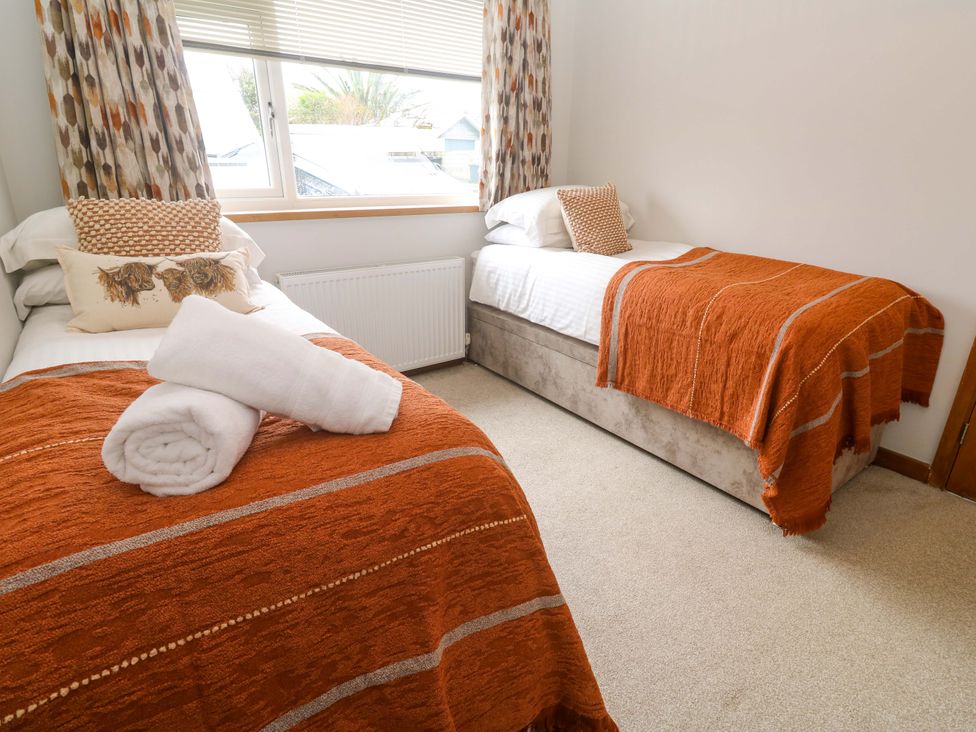 A bedroom with two beds and a window at Byron’s Retreat Crantock