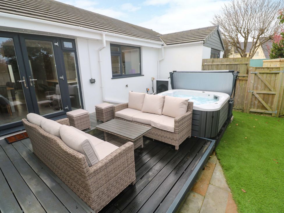 An outdoor patio with a hot tub and seating area at Byron’s Retreat in Crantock