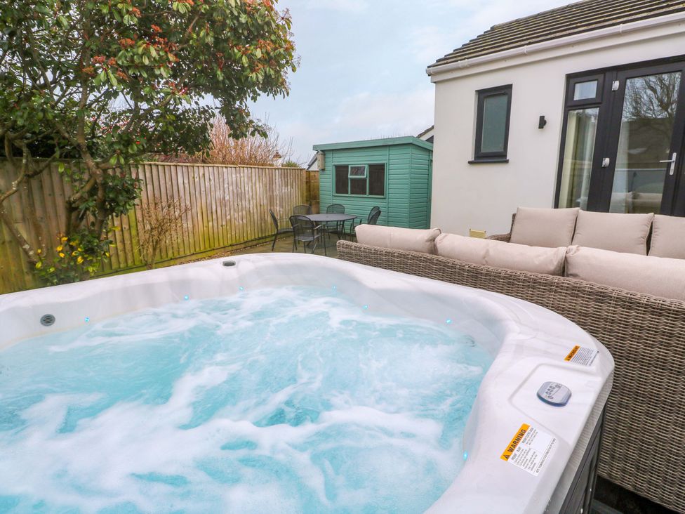 A garden with a hot tub and outdoor seating at Byron’s Retreat in Crantock