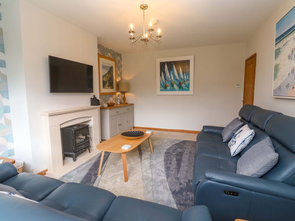 A living room with a sofa, coffee table, and television at Byron’s Retreat in Crantock