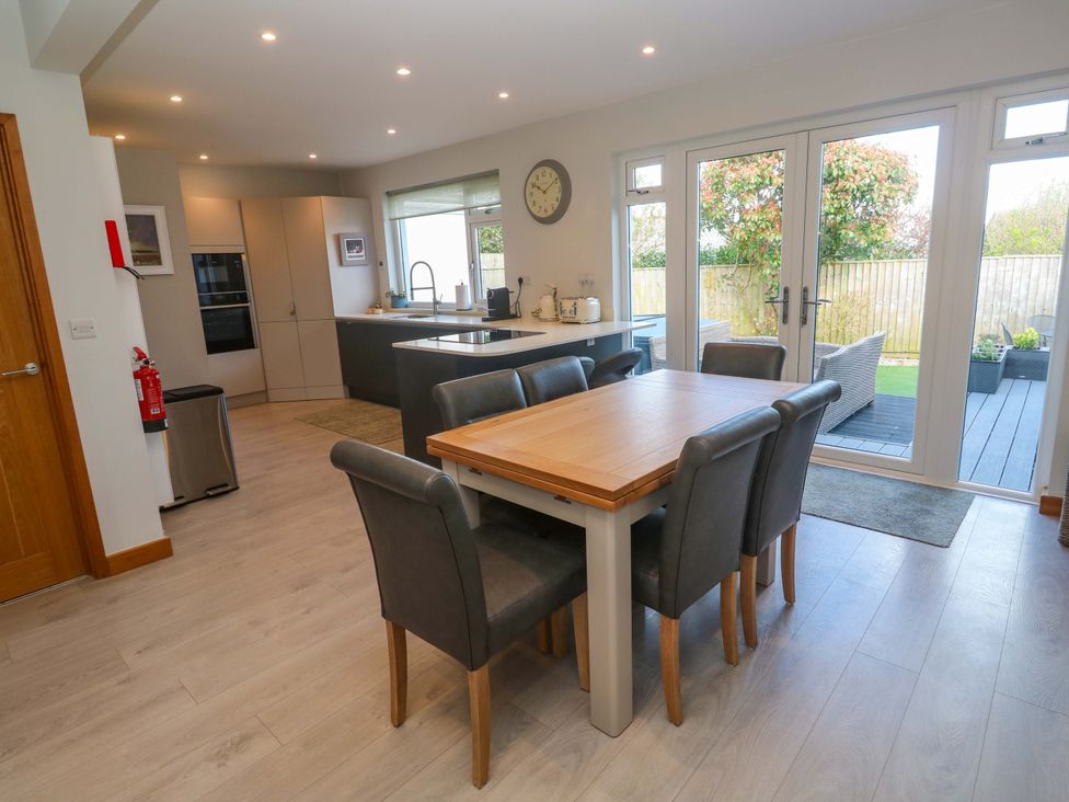 A kitchen with a dining table and access to a patio at Byron’s Retreat in Crantock