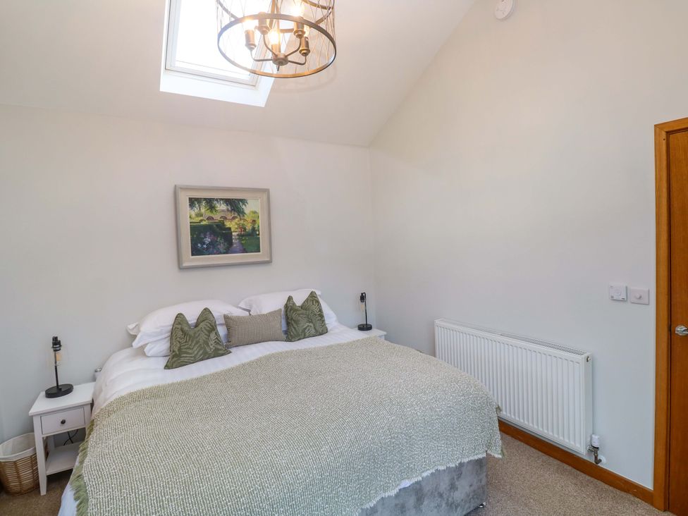 A bedroom with a bed and bedside table at Byron’s Retreat Crantock