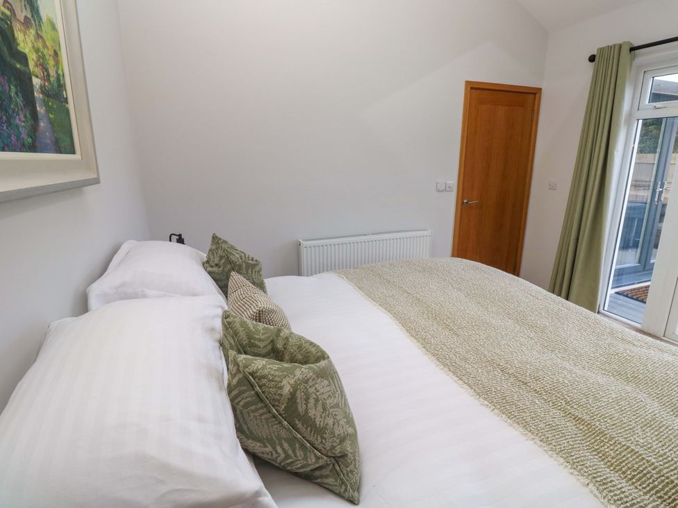 A bedroom with a bed and a door at Byron’s Retreat in Crantock