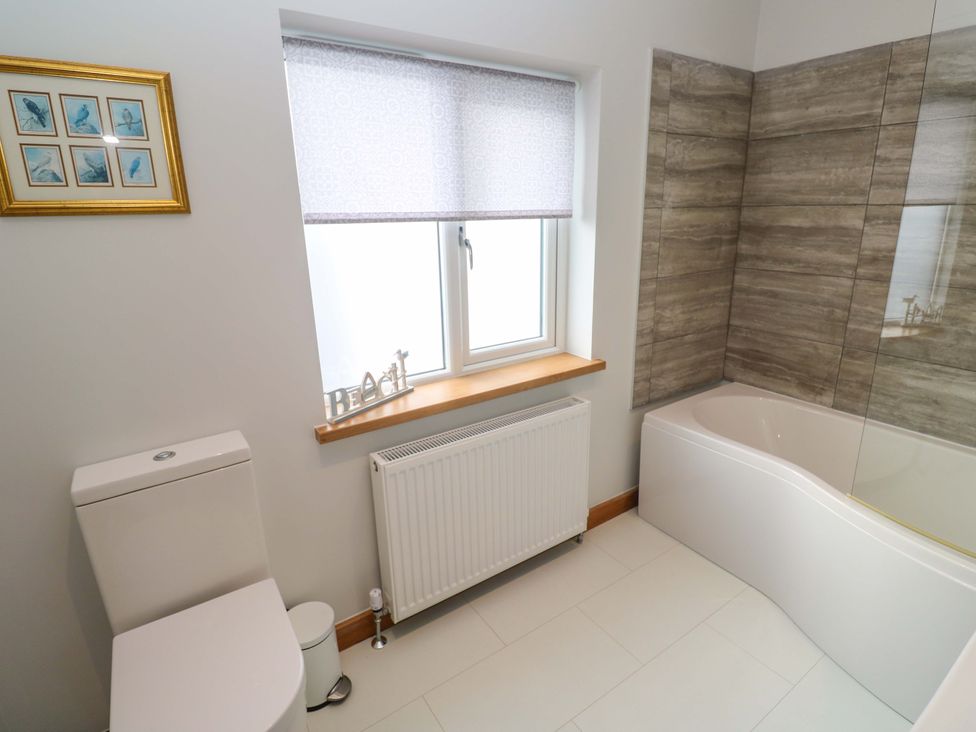 A bathroom with a bathtub and toilet at Byron’s Retreat in Crantock