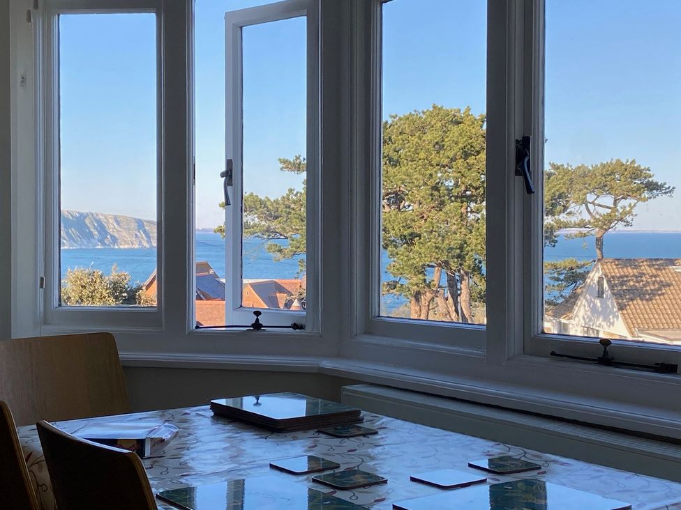 A dining room with a view of the sea and coast at Purbeck Vista in Swanage