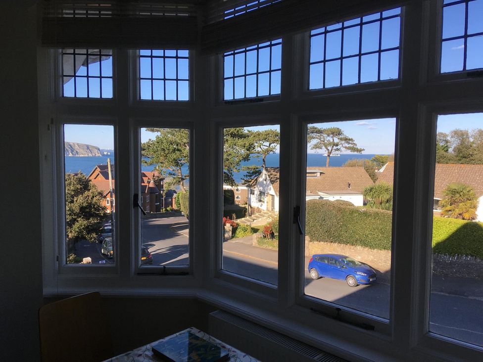A view of the sea and houses through a window at Purbeck Vista in Swanage