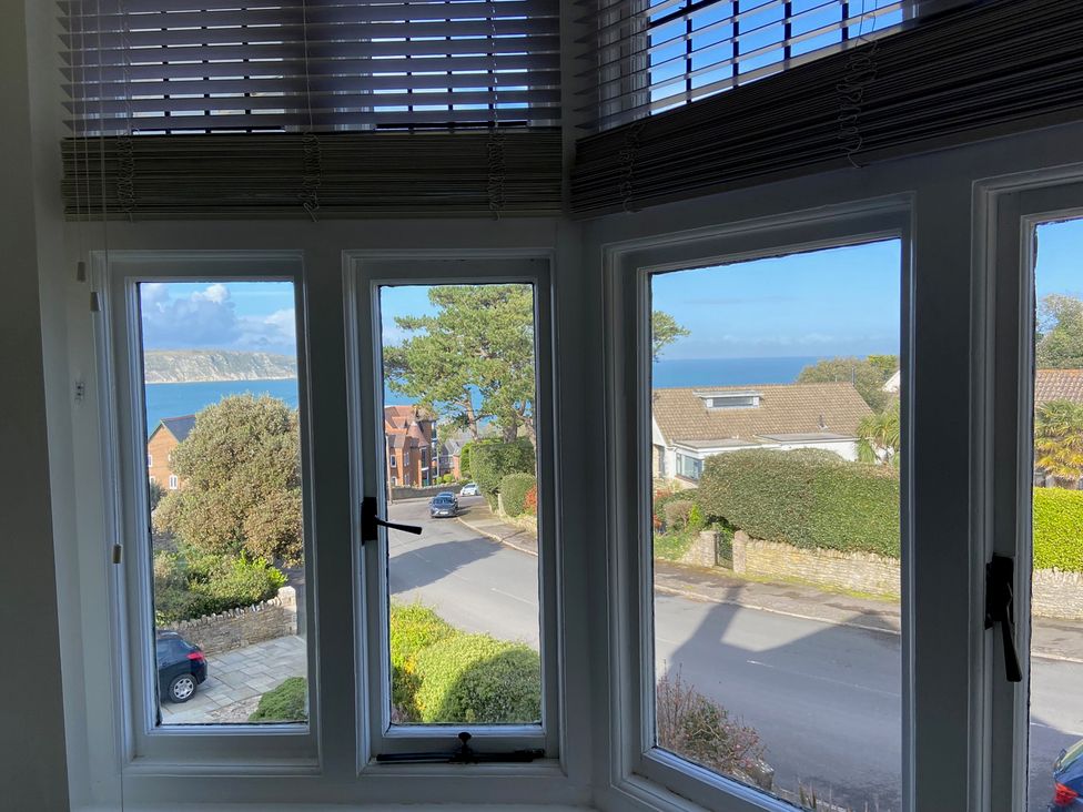 A view from a window showing trees and houses by the ocean at Purbeck Vista in Swanage