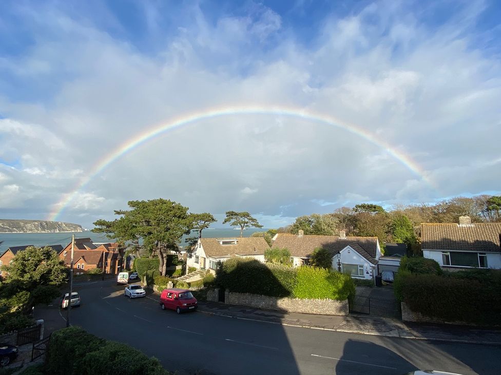 An outdoor view with a rainbow over houses and a road at Purbeck Vista in Swanage