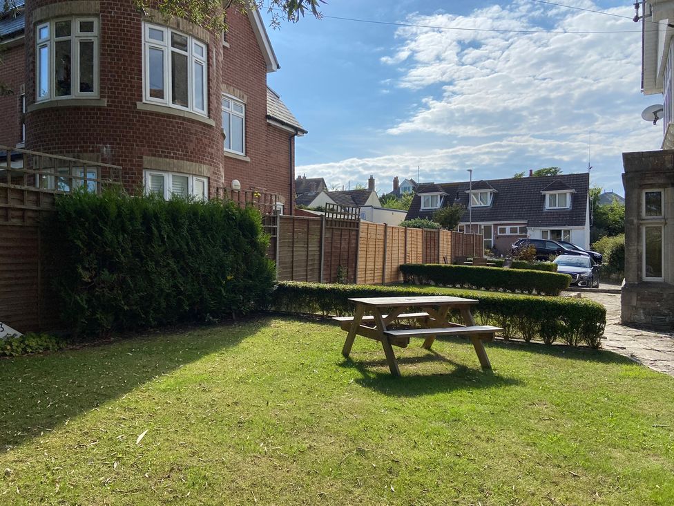 A garden with a picnic table and hedges at Purbeck Vista in Swanage