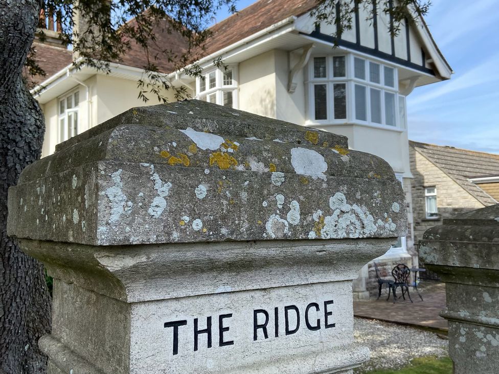 A house labeled The Ridge with a stone sign in front at Purbeck Vista Swanage