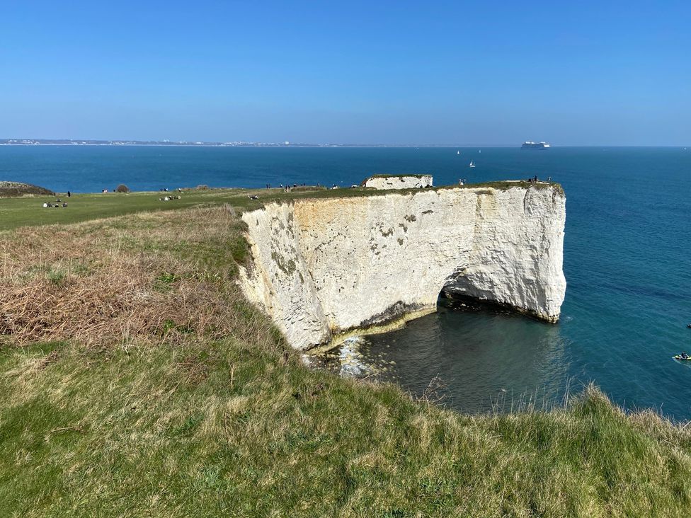 A cliff overlooking the ocean with people in the background at Purbeck Vista in Swanage