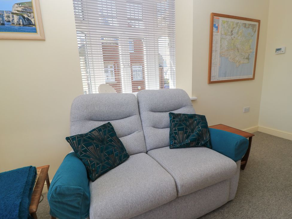A living room with a sofa and a map on the wall at Purbeck Vista in Swanage