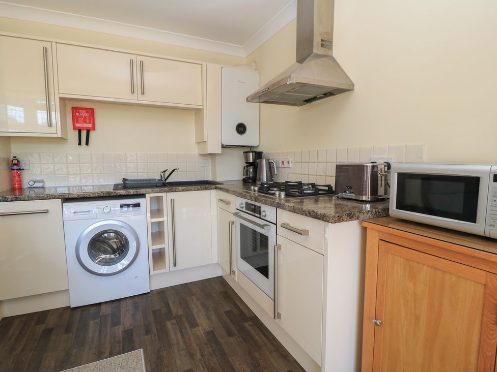 A kitchen with appliances including a washing machine and microwave at Purbeck Vista in Swanage