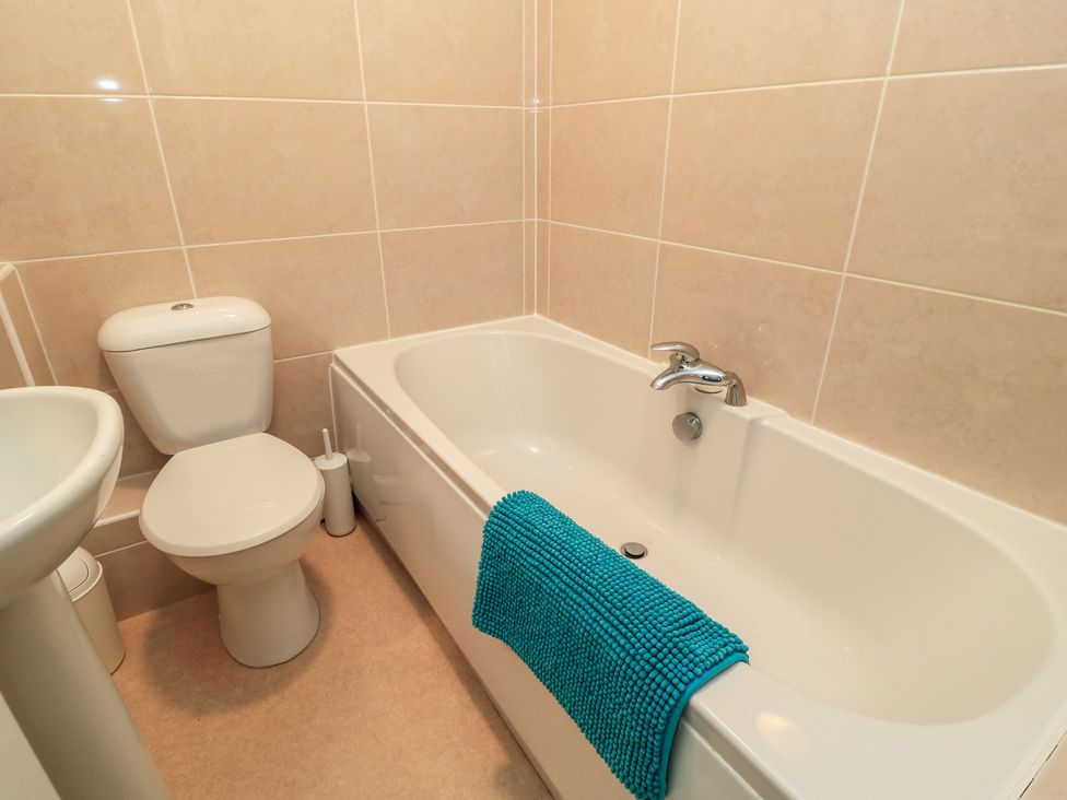 A bathroom with a bath tub, toilet, and sink at Purbeck Vista in Swanage