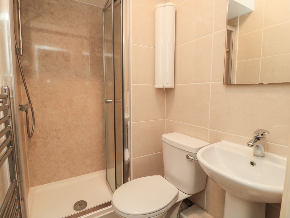 A bathroom with shower, toilet, sink and mirror at Purbeck Vista in Swanage