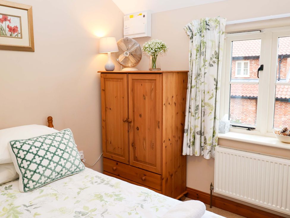 A bedroom with a bed, wardrobe, and lamp at Hayloft in Ipswich