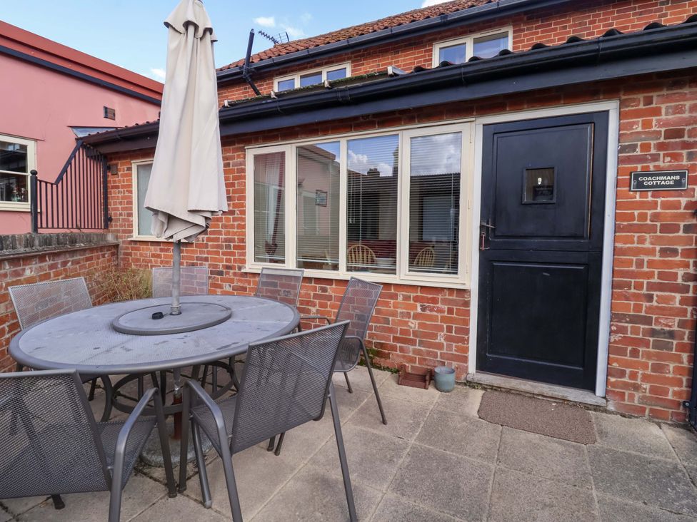 An outdoor dining area with a table and chairs at Coachman's Cottage in Ipswich