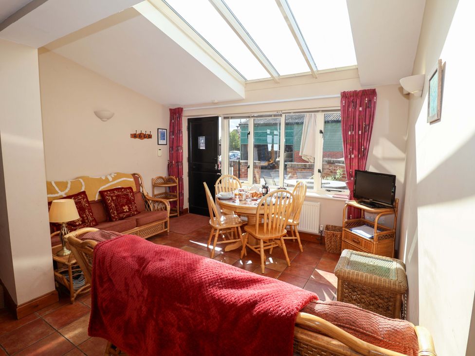 A living room with a sofa and dining area at Coachman's Cottage Ipswich