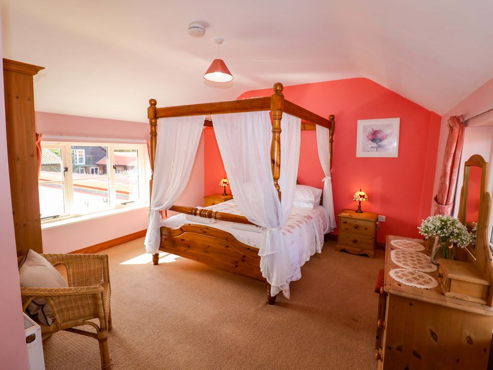 A bedroom with a four-poster bed and a dresser at Coachman's Cottage in Ipswich