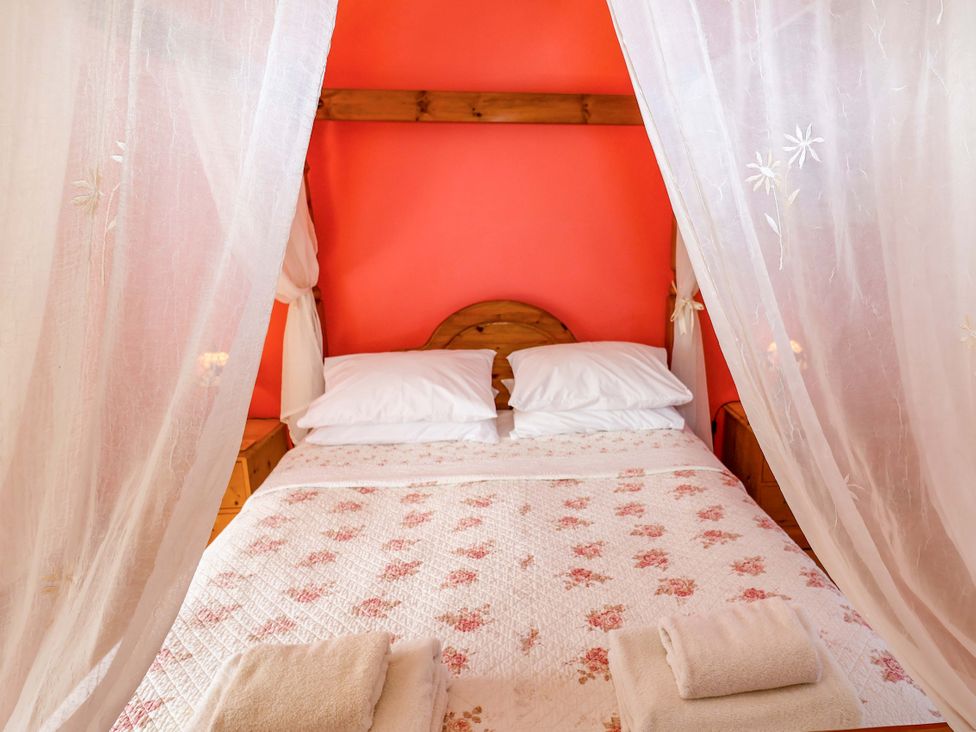 A bed with pillows and towels in a bedroom at Coachman's Cottage, Ipswich