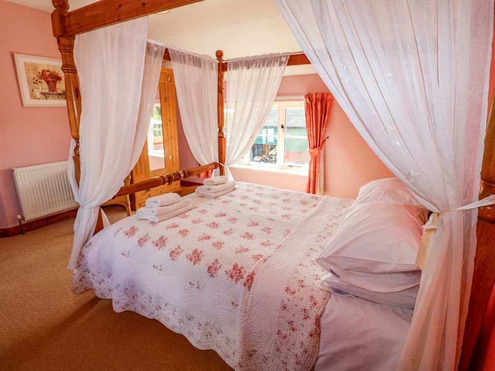A bedroom with a four-poster bed and towels at Coachman's Cottage Ipswich