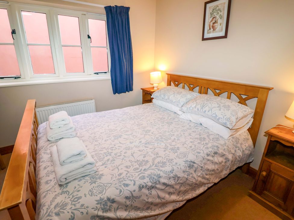 A bedroom with a bed and bedside tables at Coachman's Cottage in Ipswich